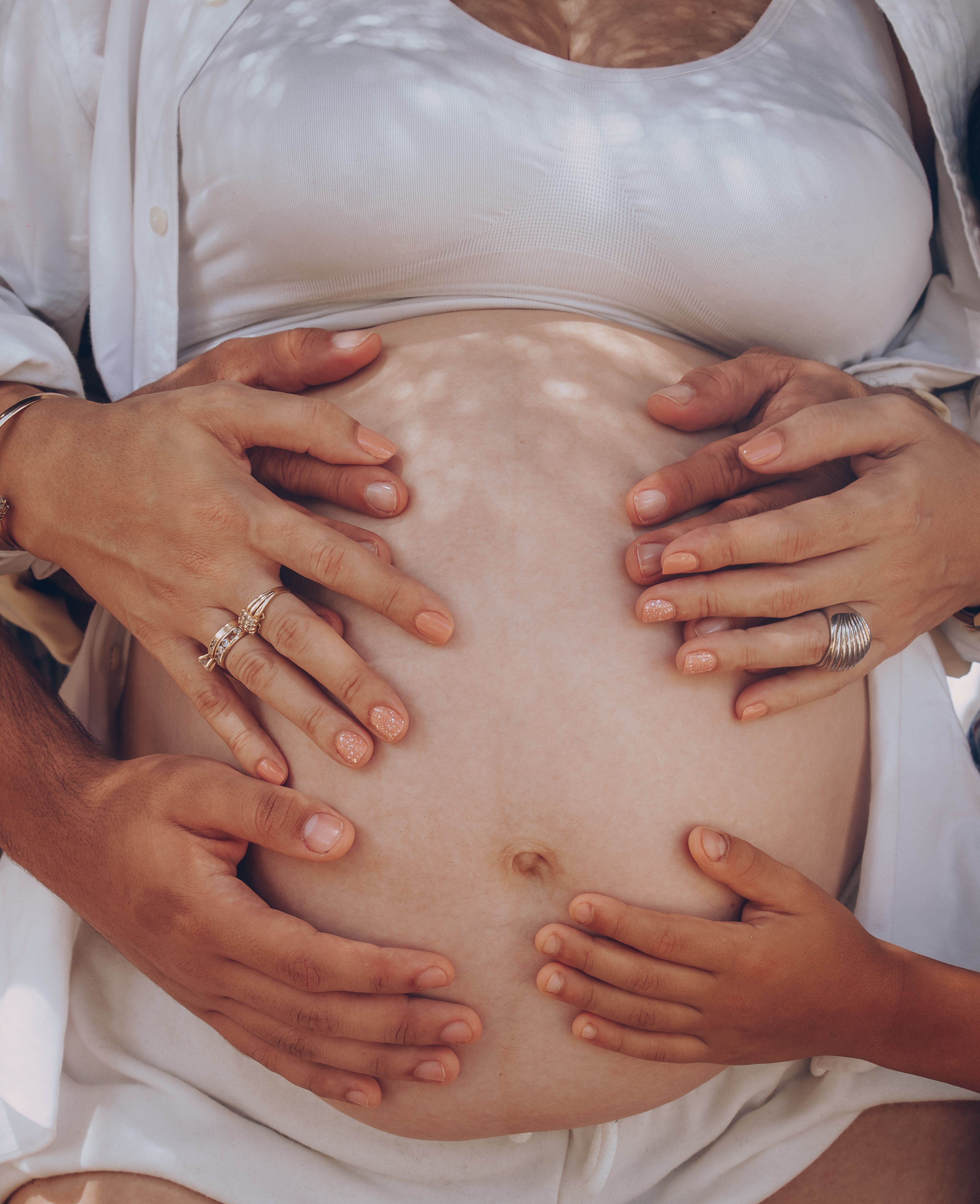 Una familia pone las manos en el vientre de una mujer embarazada. Foto: Elias Suárez (Pexels).