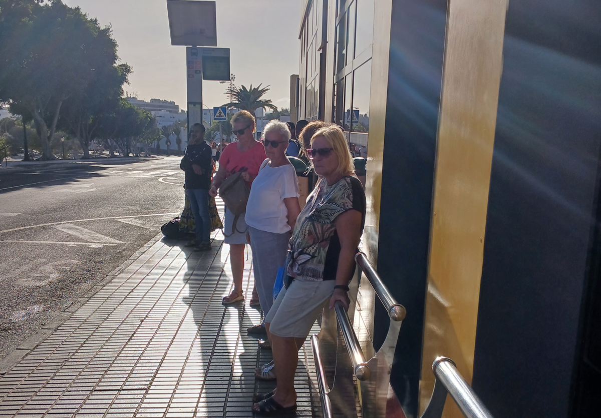 Usuarios en una parada de guaguas sin marquesina ni protección contra el sol