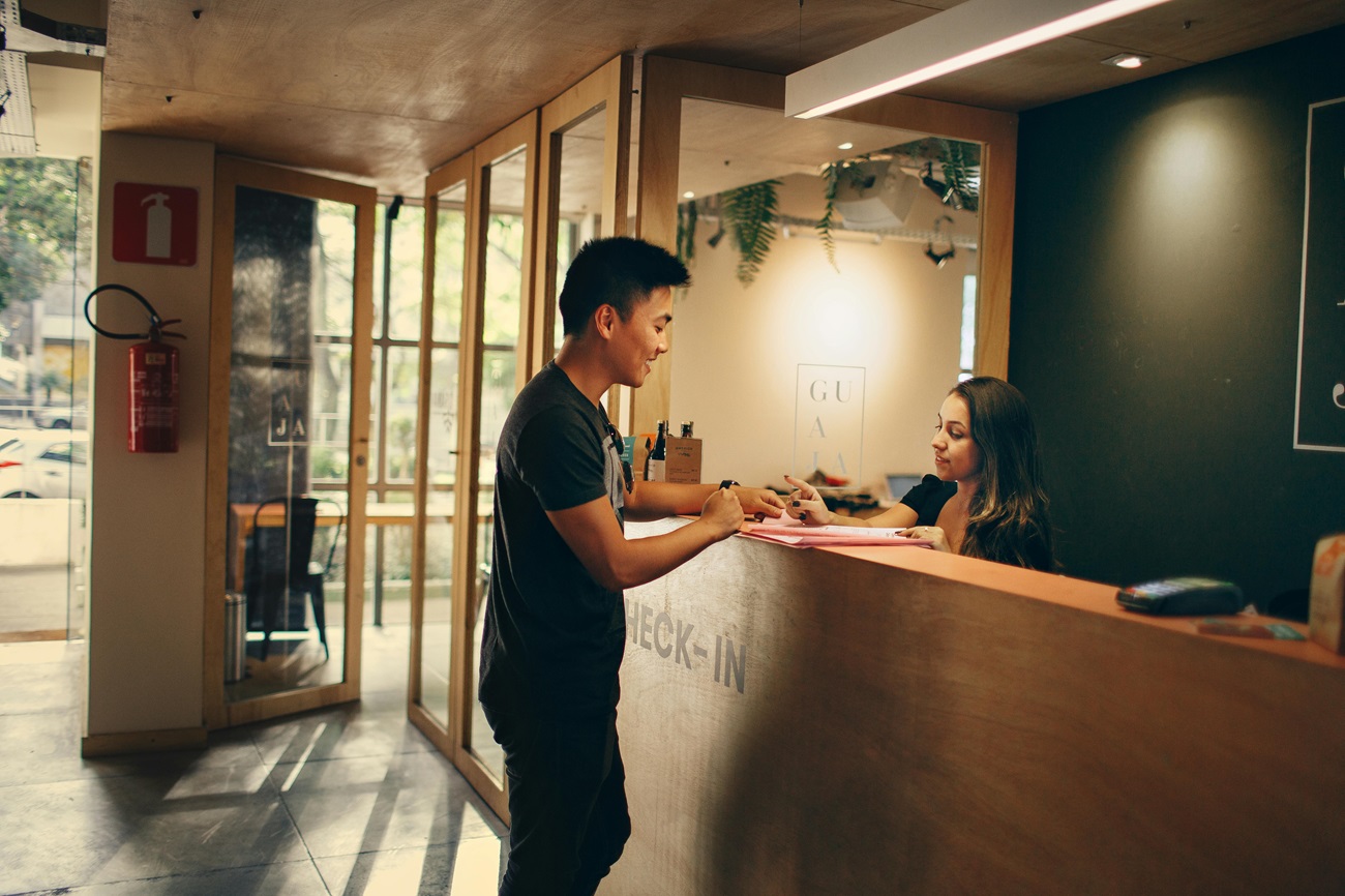 Un turista a su llegada a la recepción de su hotel. Hoteleros.