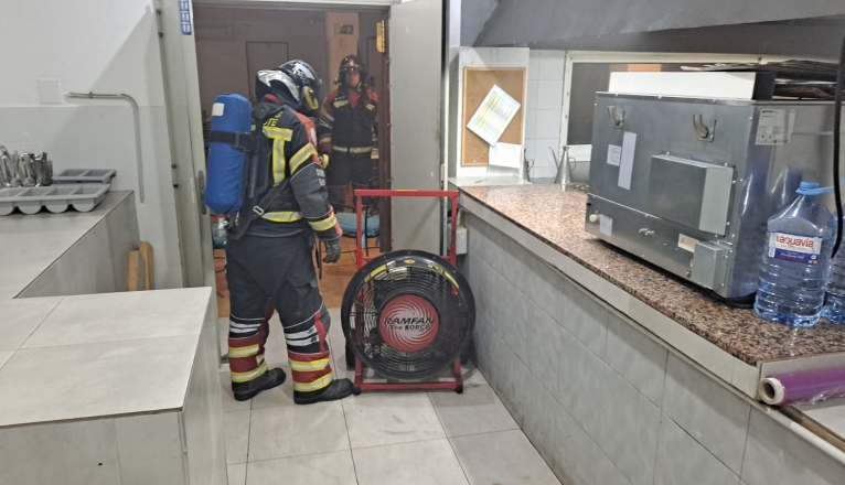 Bomberos sofocando el incendio en la cocina del hotel.