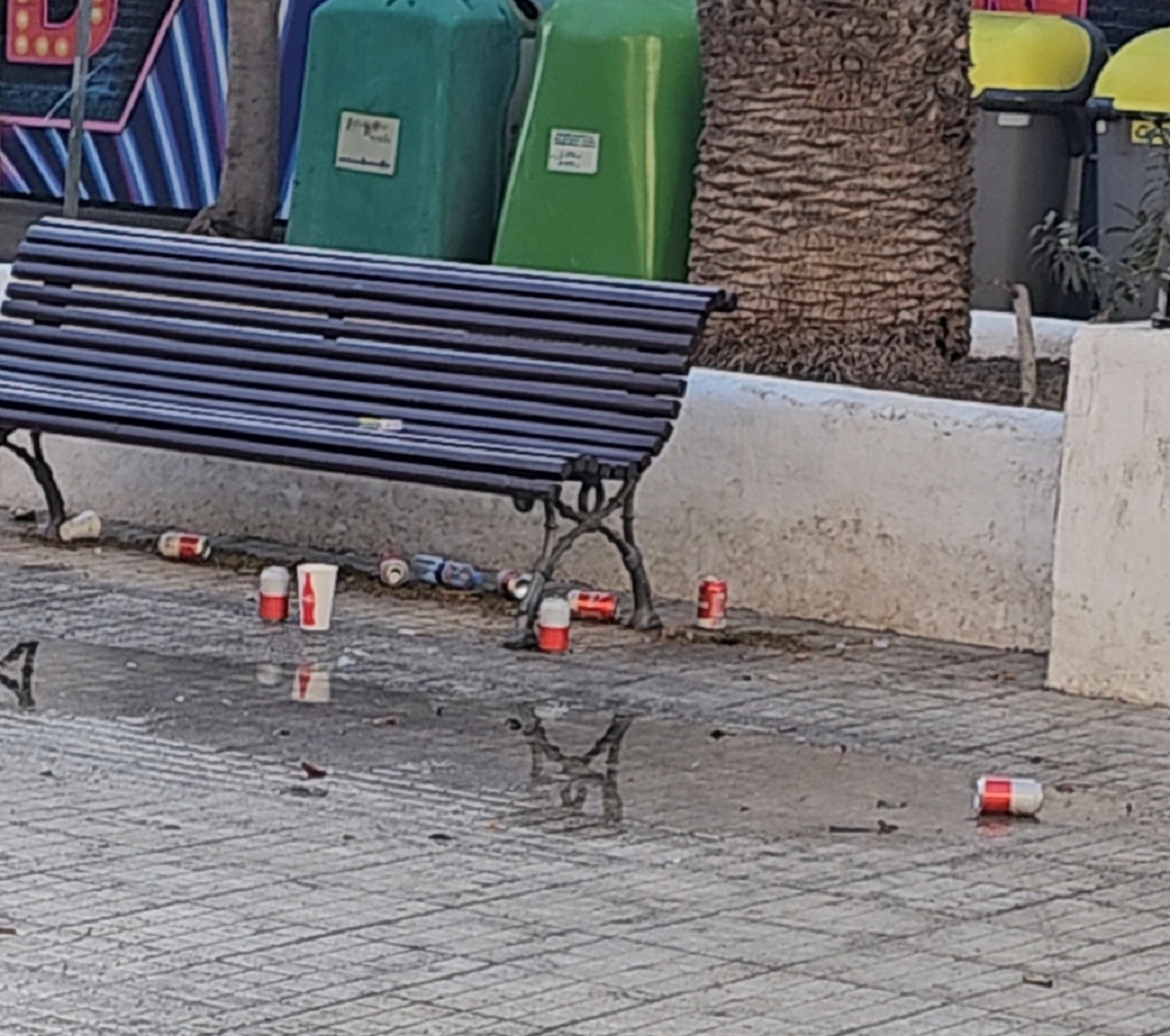 Un banco con cervezas, latas de refresco y vasos de plástico.