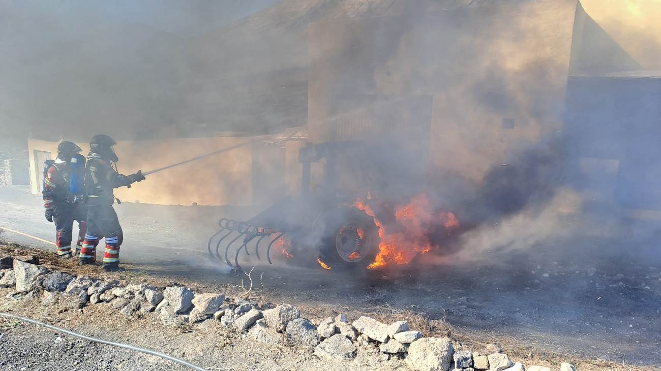 Bomberos apagando el fuego de un tractor